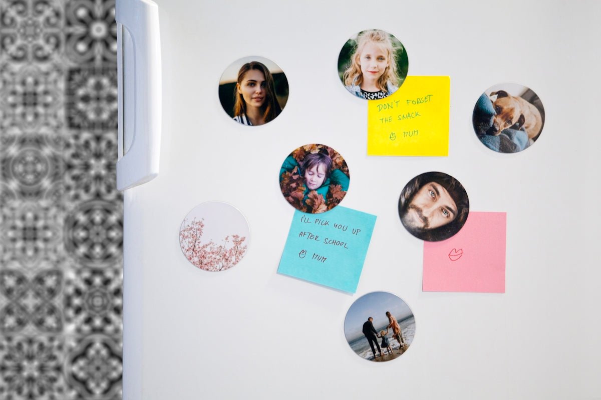 Round photo magnets and colorful notes displayed on a white refrigerator